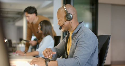 Delivering customer support: diverse team collaborating in open-plan office with headsets