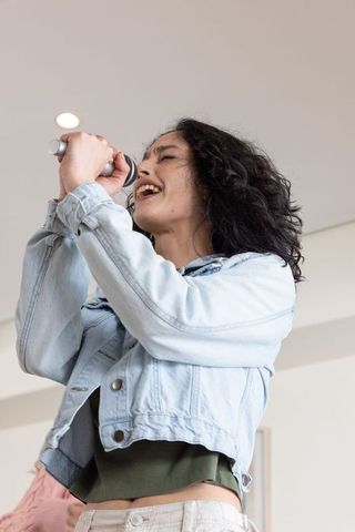 Energetic female vocalist singing into handheld microphone during rehearsal