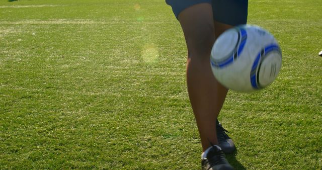 Close-up of a soccer player's leg kicking a ball on the field, with copy space. Action shot captures the dynamic movement during a soccer game outdoors.