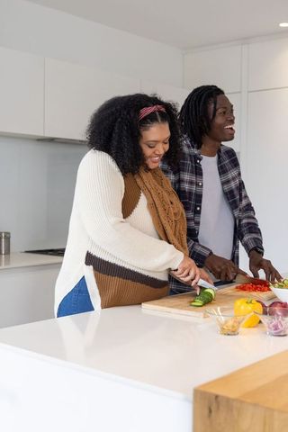 African american couple cooking together in modern kitchen preparing fresh vegetables