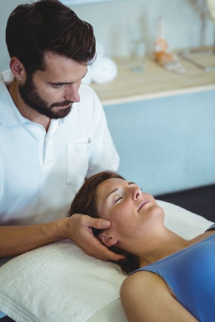 Physiotherapist giving head massage to a woman in clinic