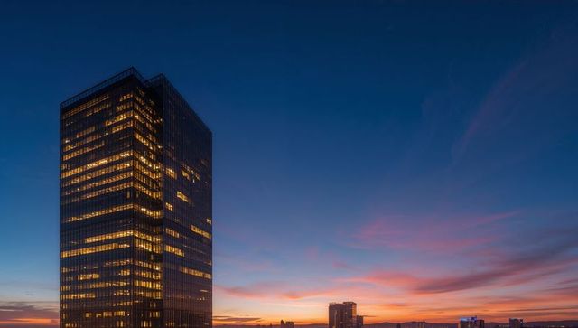 Glass Office Tower Glowing at Dusk with Vibrant Sunset Gradient and City Horizon
