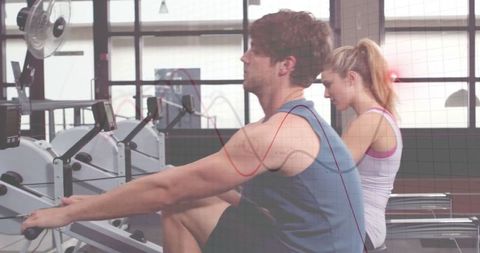 Partners rowing together at gym for strength and fitness