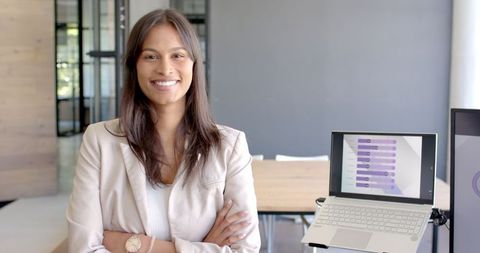 Confident Businesswoman Standing by Laptop in Modern Office