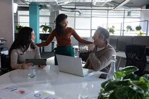 Multiracial Team Collaborating in Modern Open-Plan Office Using Laptop and Tablet