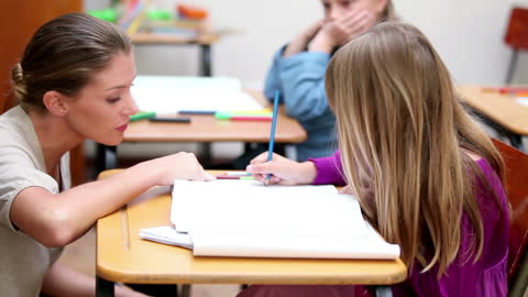 Teacher Giving Guidance to Student at Desk