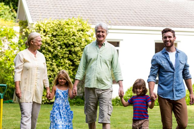 Multigenerational family enjoying time together outdoors, walking hand in hand in a garden. Ideal for use in advertisements, family-oriented content, lifestyle blogs, and promotional materials emphasizing family values and togetherness.