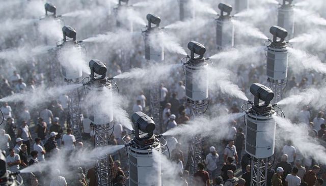 Cooling mist towers spraying over festival crowd for heat relief and outdoor event comfort