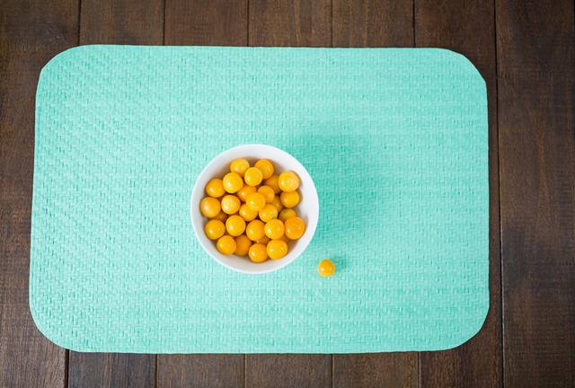 Top view of a bowl filled with fresh yellow cherries placed on a wooden board. The vibrant colors and rustic background make this image perfect for use in food blogs, healthy eating articles, and summer recipe websites.