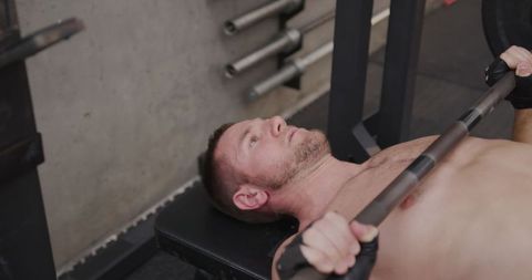 Caucasian Male Weightlifter Performing Bench Press at Gym