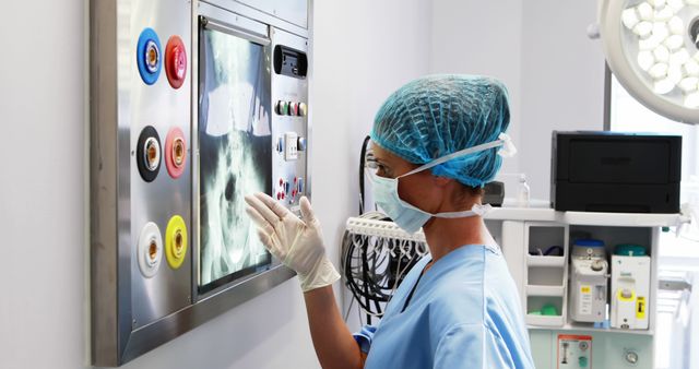 Healthcare professional wearing PPE examining medical X-ray. Ideal for articles on medical diagnostics, healthcare workers, patient care, radiology, and hospital environments.