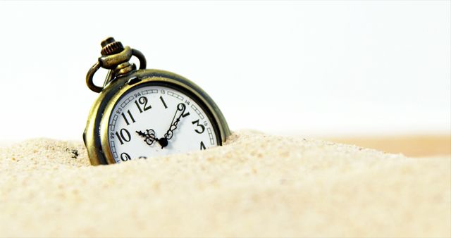 A vintage pocket watch is partially buried in sand, symbolizing the passage of time or a reminder of fleeting moments. Its classic design evokes nostalgia and the importance of cherishing time.