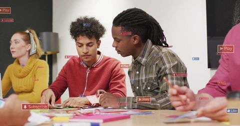 Young adults collaborating at craft table cutting paper and brainstorming in makerspace