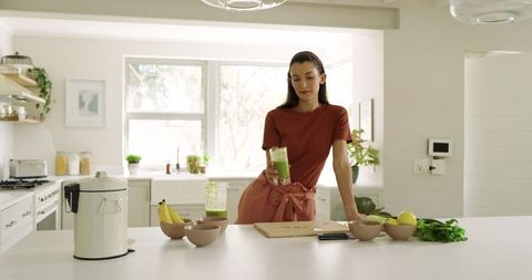 Woman in Modern Kitchen Holding Green Smoothie