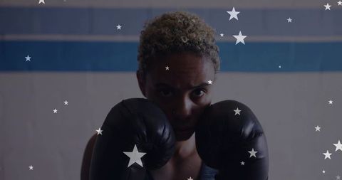 Woman boxing holding guard with gloves in gym training with star overlay