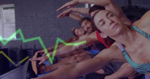 Group stretching class reaching forward with focused woman leading flexibility workout