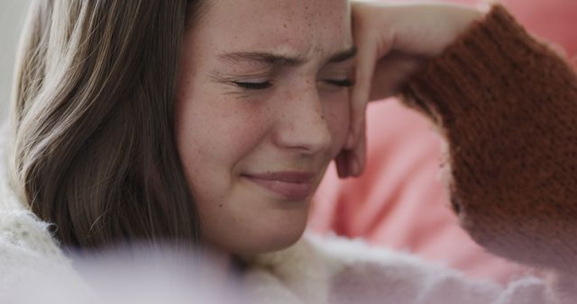 Teen girl is feeling distressed with her hand on her forehead, conveying intense emotion. Useful for depicting emotions, mental health, teenage struggles, or scenes requiring an expression of sadness or stress.