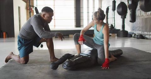 Instructor guiding martial arts trainee in boxing gym