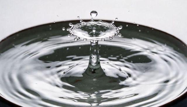 Water droplet crown forming on rising column creating concentric ripples