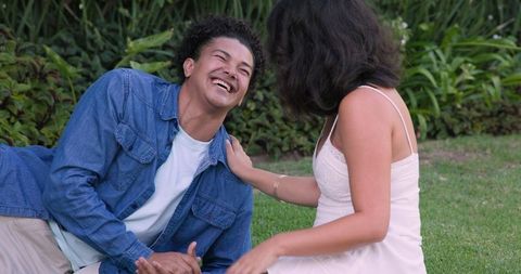 Joyful Couple Laughing Together Outdoors on Grass