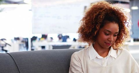 Smiling Woman Reviewing Notes in Modern Office Lounge
