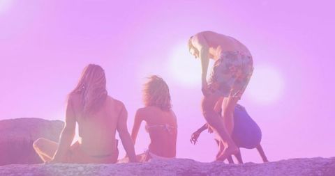 Friends Relaxing on Beach Outcrop During Vibrant Sunset Scene