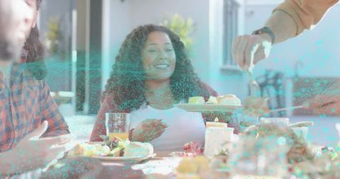 Smiling woman receiving pastry while holding glass of juice at bright casual brunch table