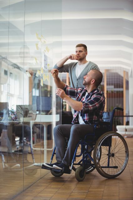 Businessman in Wheelchair Collaborating with Colleague on Project - Download Free Stock Images Pikwizard.com