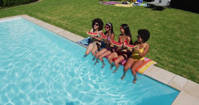 Overhead view of group of diverse girls eating watermelon while sitting by the pool. youth friendship and pool party concept