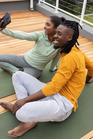 Indian woman and african american man taking selfie after rooftop yoga session