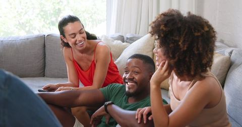 Diverse Friends Relaxing on Sofa Using Smartphone and Smartwatch