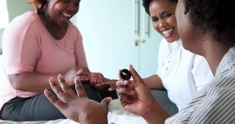 Friends Enjoying Manicure Together in Cozy Bedroom Setting