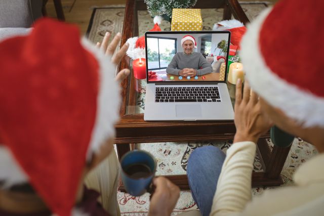 Diverse couple with santa hats having video call with happy caucasian man. Christmas, celebration and digital composite image.