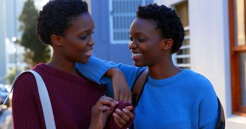 African American Twin Sisters Laughing in Urban Street Scene