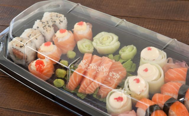 Close-up of set of assorted sushi kept in a plastic box on wooden table
