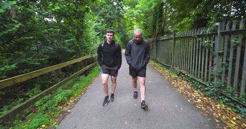 Two men hiking forest path in athletic gear