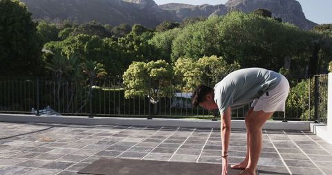 Asian Male Stretching on Balcony Against Mountainous Backdrop