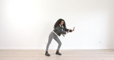 Energetic Young Woman Dancing Indoors on Wooden Floor