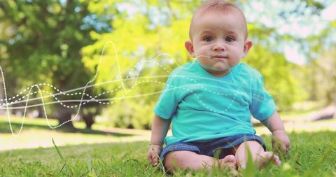 Curious baby boy sitting on grass showing bracelet in sunlit park with audio waveform overlay