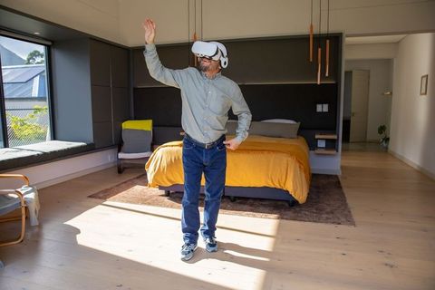 Man wearing vr headset exploring virtual reality in sunlit modern bedroom
