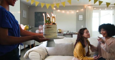 Women Celebrating Birthday with Cake in Bright Living Room