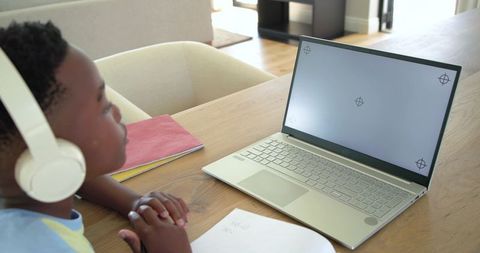 African American Child Studying Remotely Wearing Headphones Using Laptop at Home Desk
