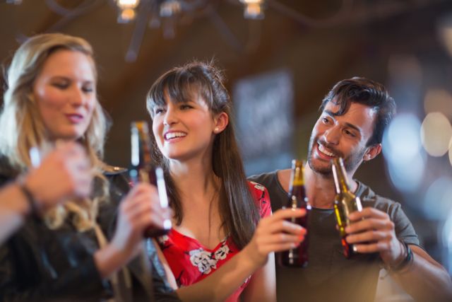 Smiling friends holding beer bottles in bar