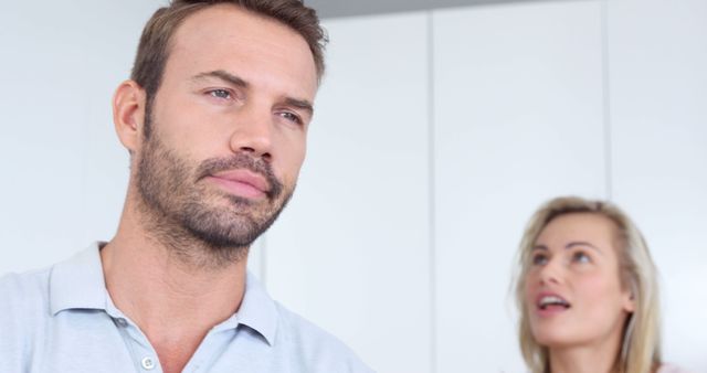 Man Contemplating with Joyful Woman Blurred in Background - Download Free Stock Images Pikwizard.com