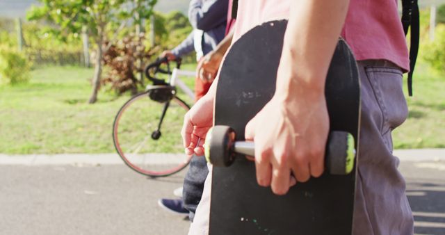 Young person holding skateboard walking in park with friends - Download Free Stock Images Pikwizard.com