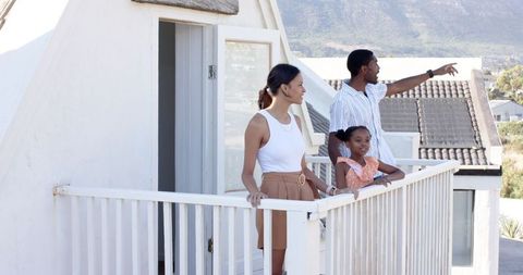 Happy Family Enjoying View from Balcony in Modern Coastal Neighborhood