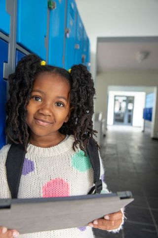 Confident African American Schoolgirl with Tablet in Modern School Corridor