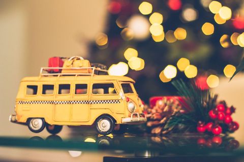 Vintage Yellow Camper Toy Van with Luggage and Festive Christmas Lights Bokeh