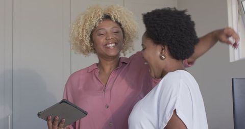 Two Caucasian Women Sharing Laughter Over Tablet in Modern Home
