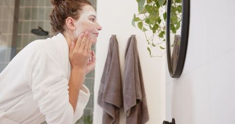 Woman Applying Facial Mask in Minimalist Bathroom